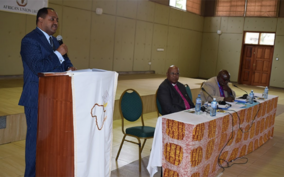 Mussie speaking on a microphone 