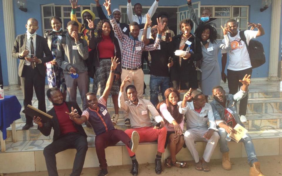 Photograph: About 20 young people sitting in two rows with their arms in the air, participants of the Malawi youth training programme